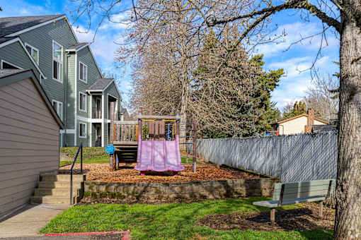 A backyard with a swing set and a fence.