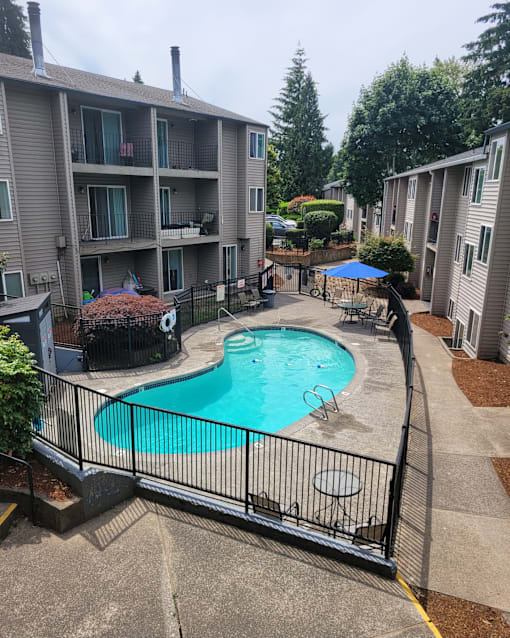 A black fence surrounds a small pool in a courtyard.