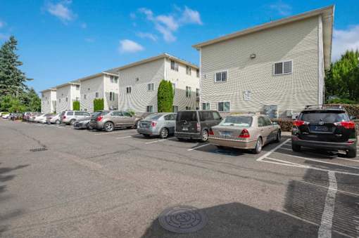 A parking lot with cars parked in front of apartment buildings.