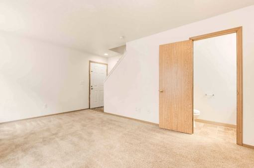 A room with a carpeted floor and two wooden doors.