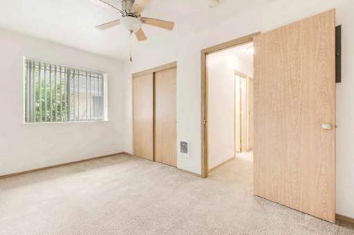 A room with a ceiling fan and a window with bars.