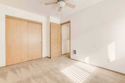 A room with a ceiling fan and two wooden doors.