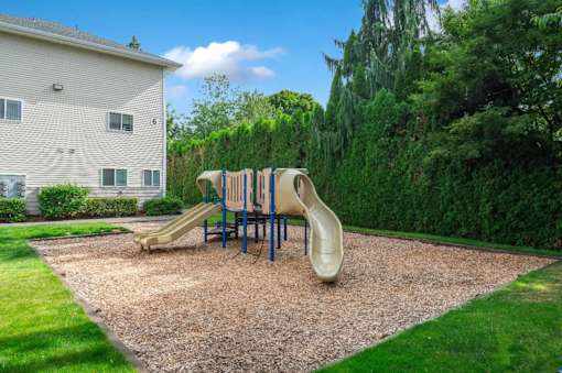 A playground with a slide and a yellow sandbox.
