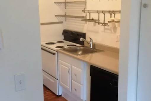 A kitchen with white cabinets and a black dishwasher.