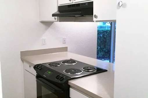 A black stove top oven with four burners and a silver oven door sits on a white countertop.