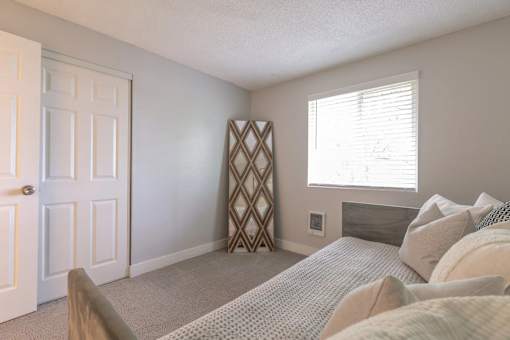 A bedroom with a bed, pillows, and a window.