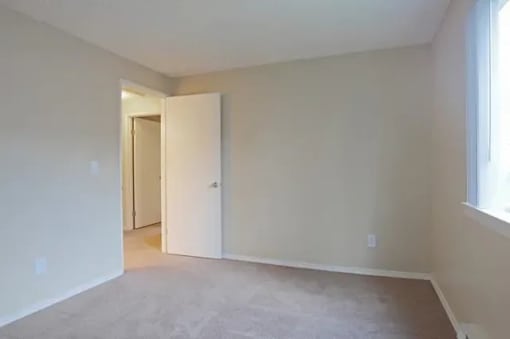 A room with a carpeted floor and a doorway leading to another room.