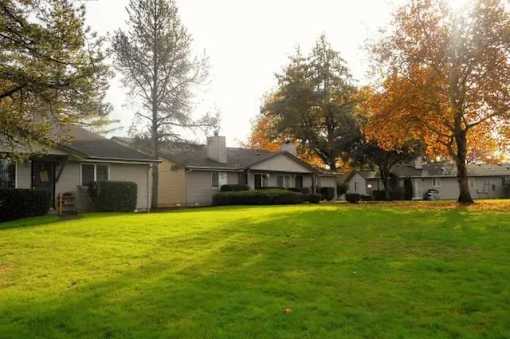 A row of houses with a green lawn in front.
