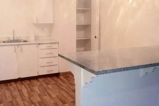 A kitchen with white cabinets and a wooden floor.