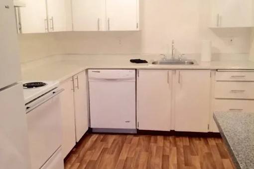 A white kitchen with wooden floors and white appliances.
