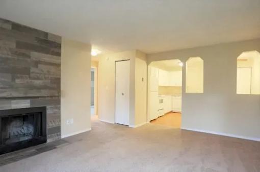 A living room with a stone fireplace and a doorway leading to another room.