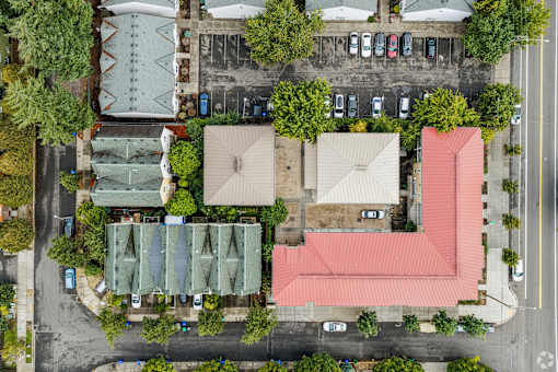 A red building is in the center of a parking lot.