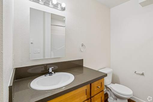 A bathroom with a toilet, sink, and mirror.