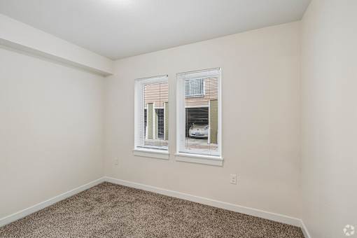 A room with two windows and carpeted floor.