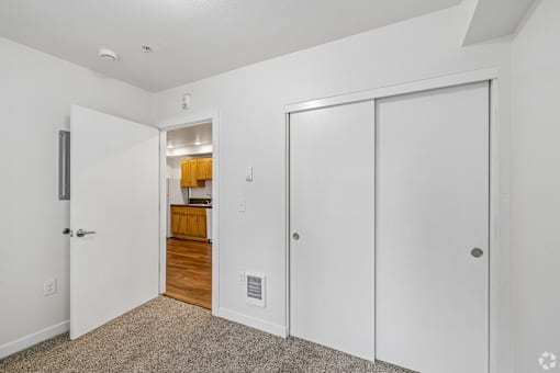 A white door is on the left of a hallway with a carpeted floor.