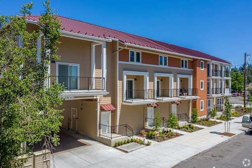 A row of townhouses with balconies and flower pots in front.