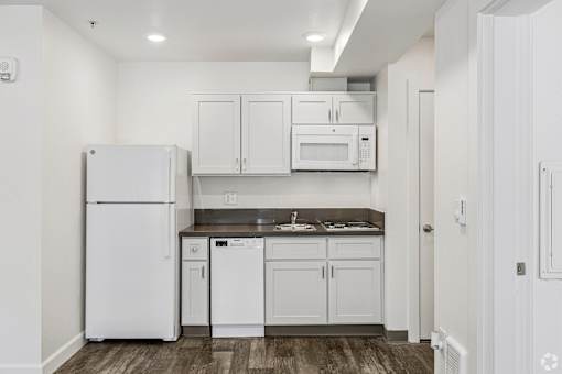 A white kitchen with a refrigerator, microwave, and cabinets.