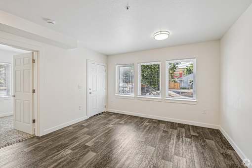 A room with a wooden floor and three pictures on the wall.