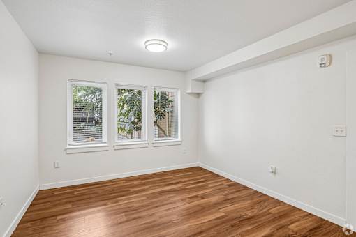 A room with wooden floors and three windows.
