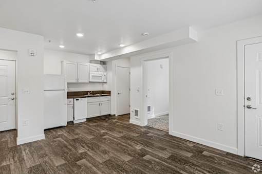 A kitchen with white cabinets and a wooden floor.