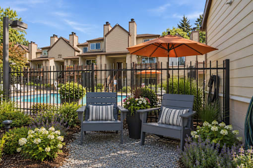 Two grey chairs are placed in front of a pool.