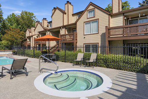 A pool with a hot tub in front of a house.