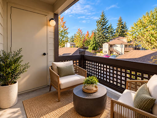 A patio with a chair, table and potted plant.