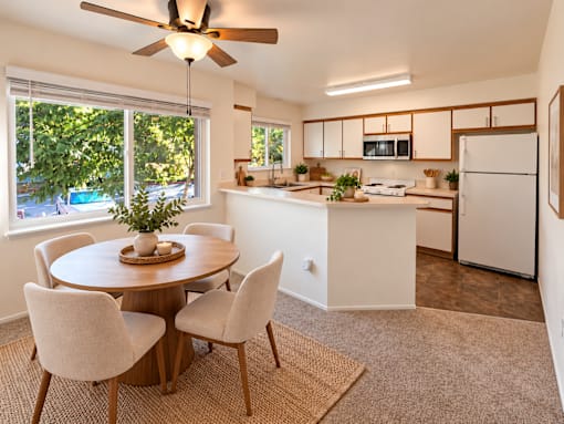 A kitchen with a table and chairs in the foreground and a refrigerator in the background.