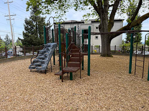 A playground with a slide, swings, and a wooden bench.