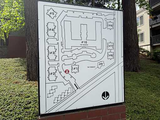 A white sign with black outlines of a maze with numbered sections and a red circle with a white number 2 in the middle.