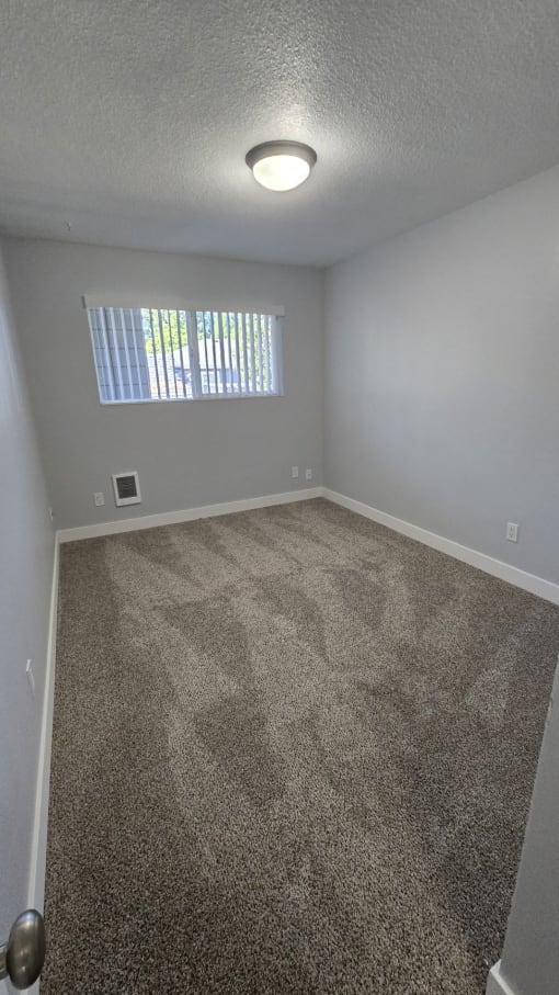 an empty bedroom with ceiling light and single window