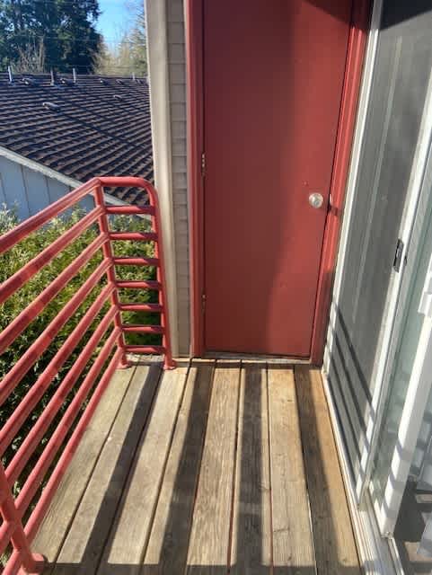 A red door is open to a wooden deck.