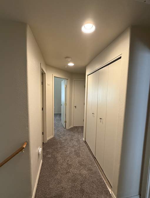 A hallway with white walls and a carpeted floor.