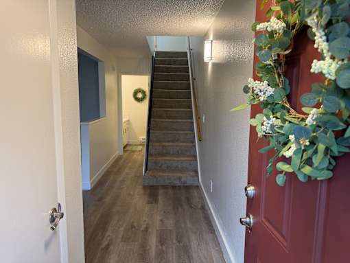 A hallway with a red door and a wreath on the wall.