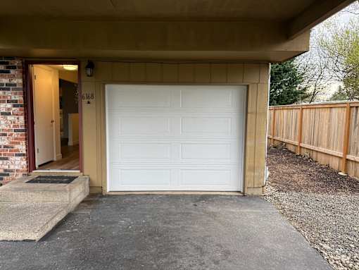 A white garage door is closed and the number 6168 is visible on the wall.