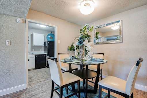 A dining room with a table set for two and a mirror above it.