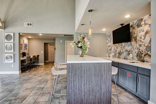 A modern kitchen with a bar area and a television mounted on the wall.