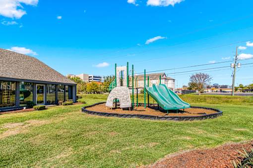 A playground with a green slide and a sandbox.