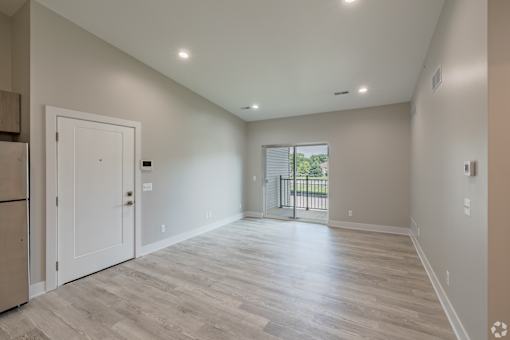 A spacious room with light wood flooring and white walls.