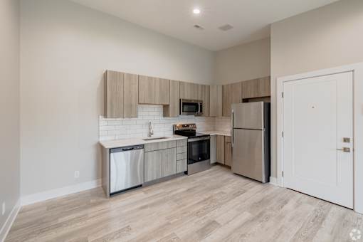 A kitchen with a refrigerator, dishwasher, and oven.
