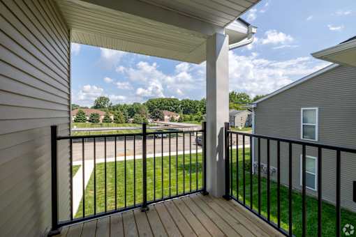 A balcony with a black railing and a view of a residential area.