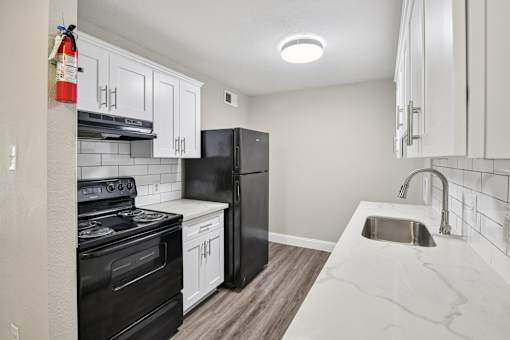 A kitchen with black appliances and white cabinets.