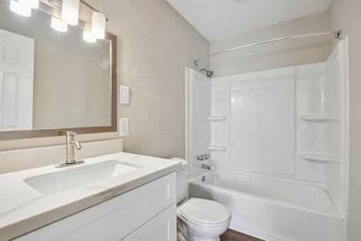 A white bathroom with a sink, toilet, and bathtub.