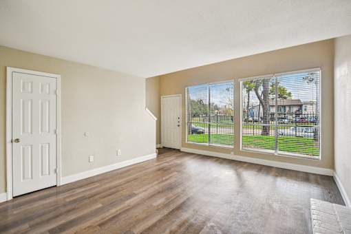 A room with a white door and a window with a view of a fence and a house.