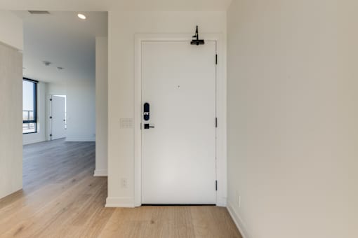 A white door with a black handle and lock in a room with wooden floors.