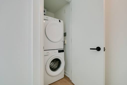 A white door opens to a small laundry room with a washer and dryer.