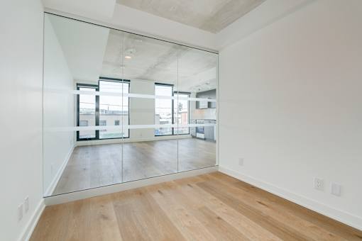 A room with a wooden floor and a large mirror on the wall.