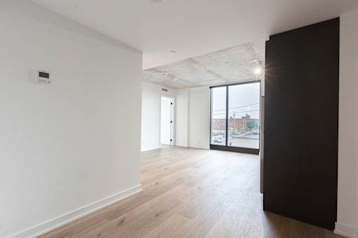 A room with a black door and a window overlooking a parking lot.