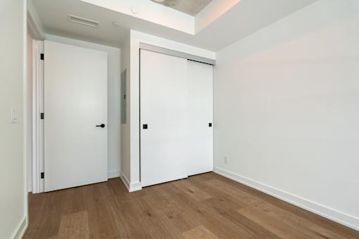 A room with two white doors and wooden floors.