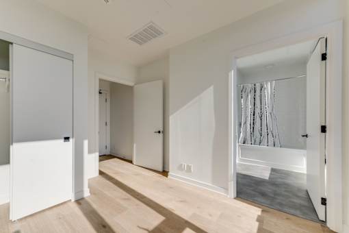 A white room with a wooden floor and a large mirror on the wall.